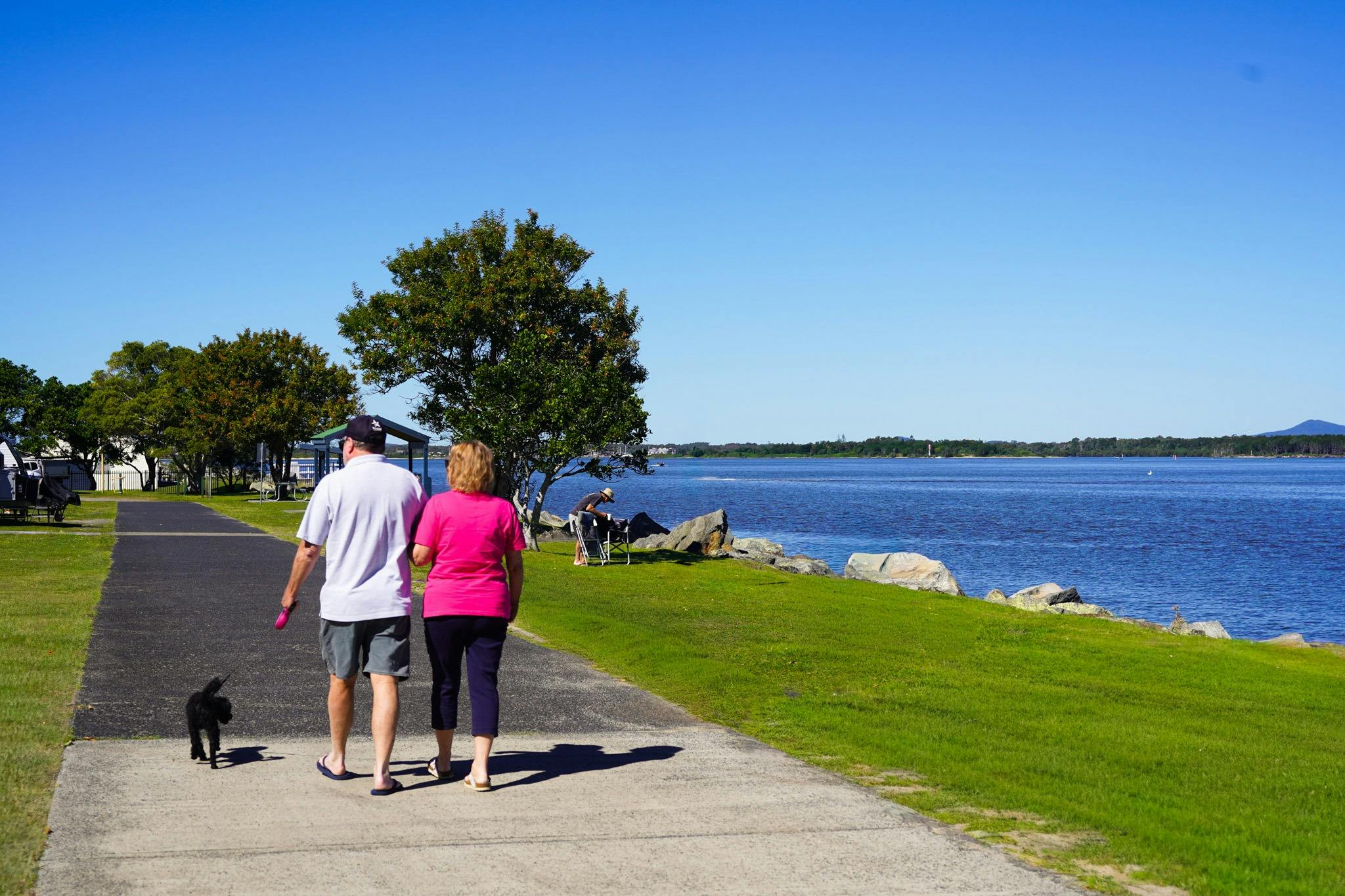 Paar geht mit Hund am Flussufer spazieren