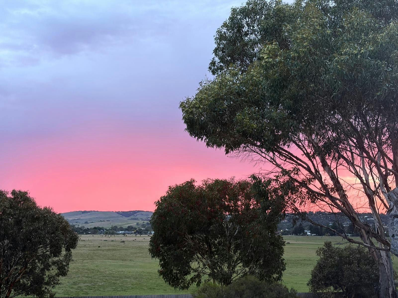 Pink sunrise glowing over the horizon, viewed from the deck at Villa 1 by The Shores.