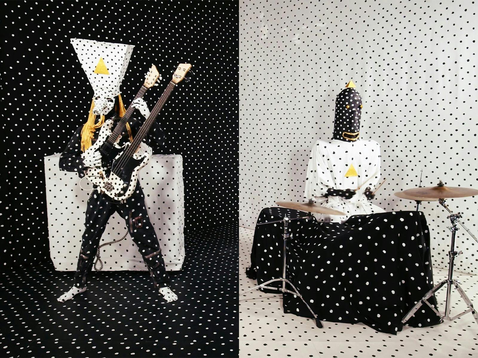 Two polka dot covered people in masks with a guitar and drums