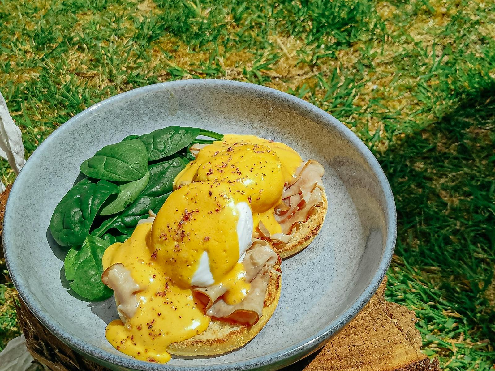A photo of eggs benedict outside in the garden.