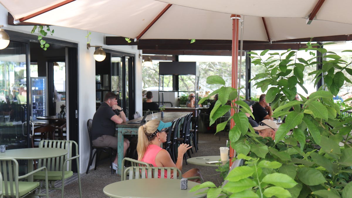 Outdoor seating area at The Pantry with greenery and modern green outdoor chairs and tables
