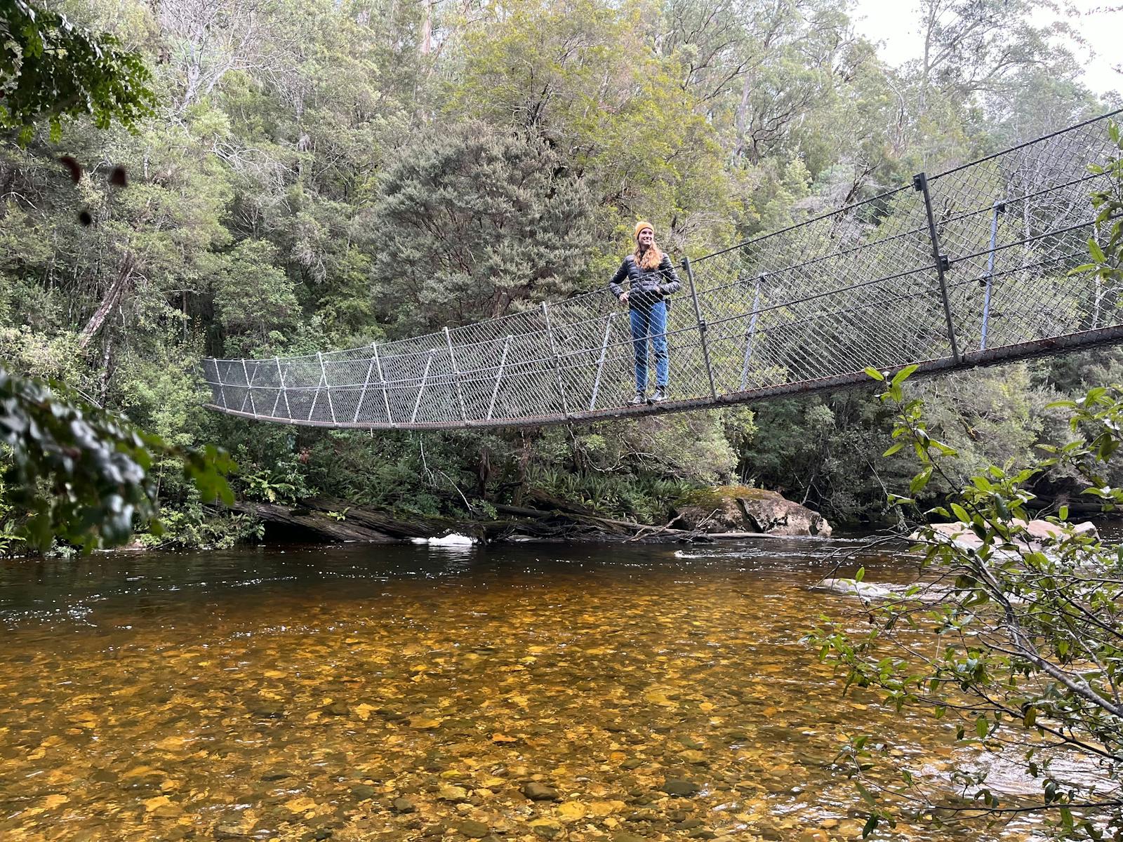 A guest stands on the suspension bridge above Franklin River on the West Coast of Tasmania
