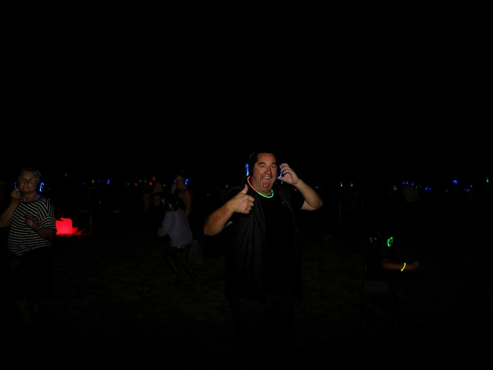 100's of people dancing on the beach atSilent Disco Under the Stars at SWELL Sculpture Festival 2024