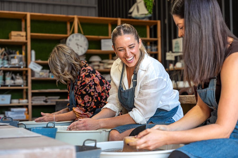 Three woman are enjoying a pottery class using the pottery wheels