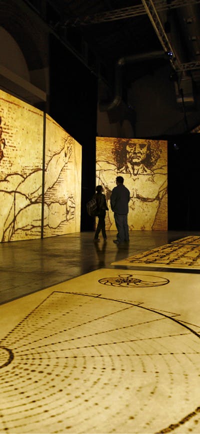 Visitors explore towering projections of Leonardo da Vinci’s sketches in an immersive gallery space.