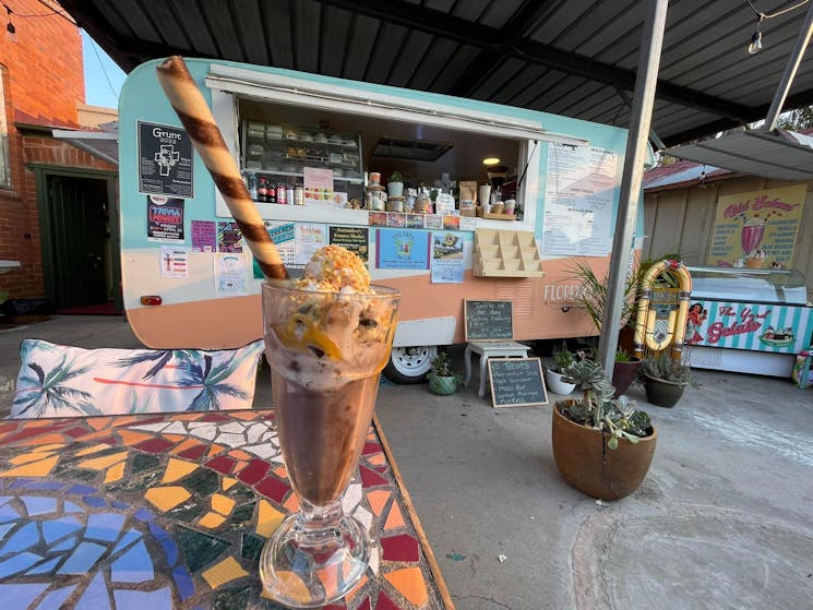 Milkshake on table in front of retro caravan cafe The Yard at Narrandera NSW
