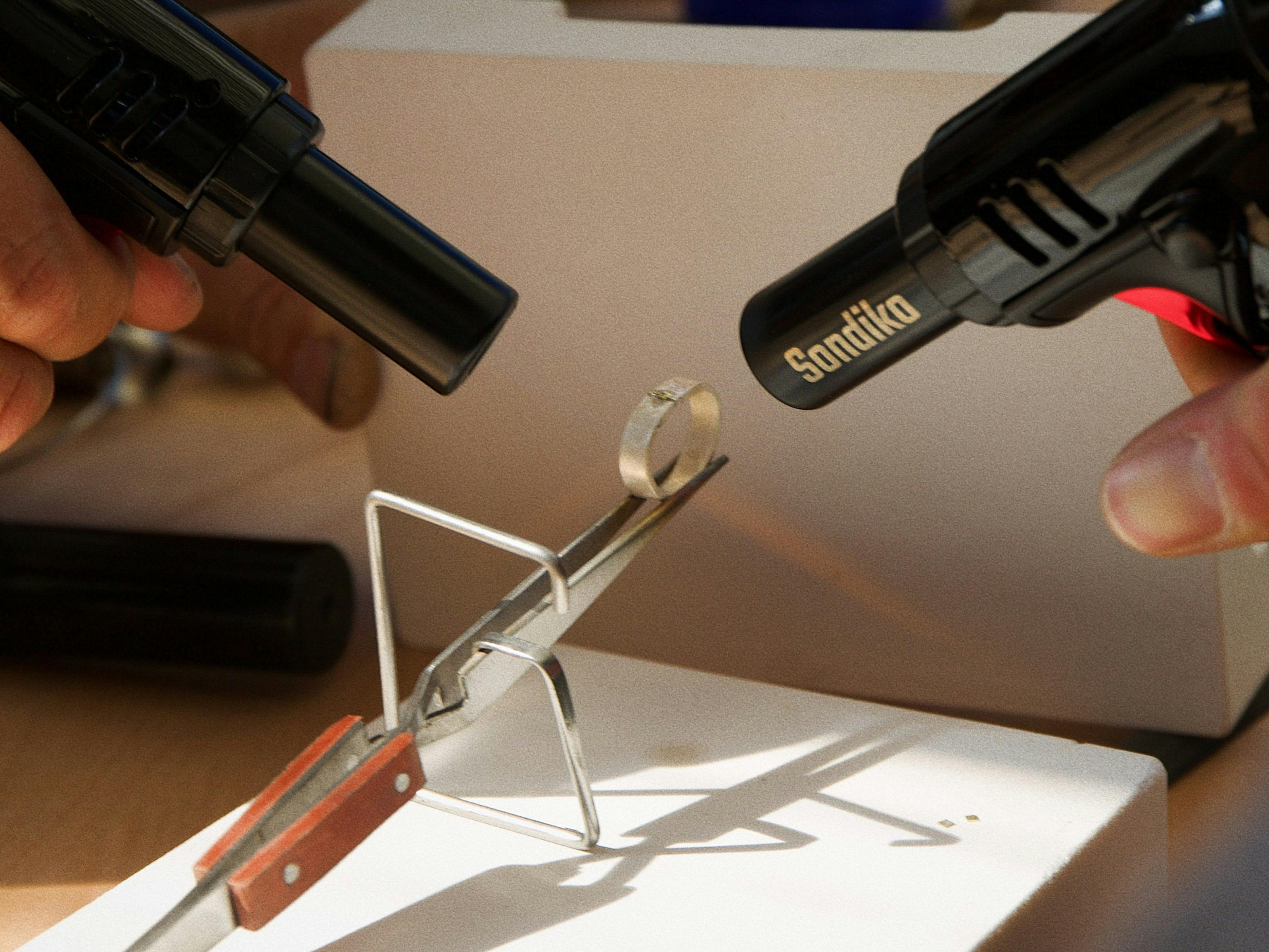 Heating the silver metal and applying solder to join the ring together with precision.