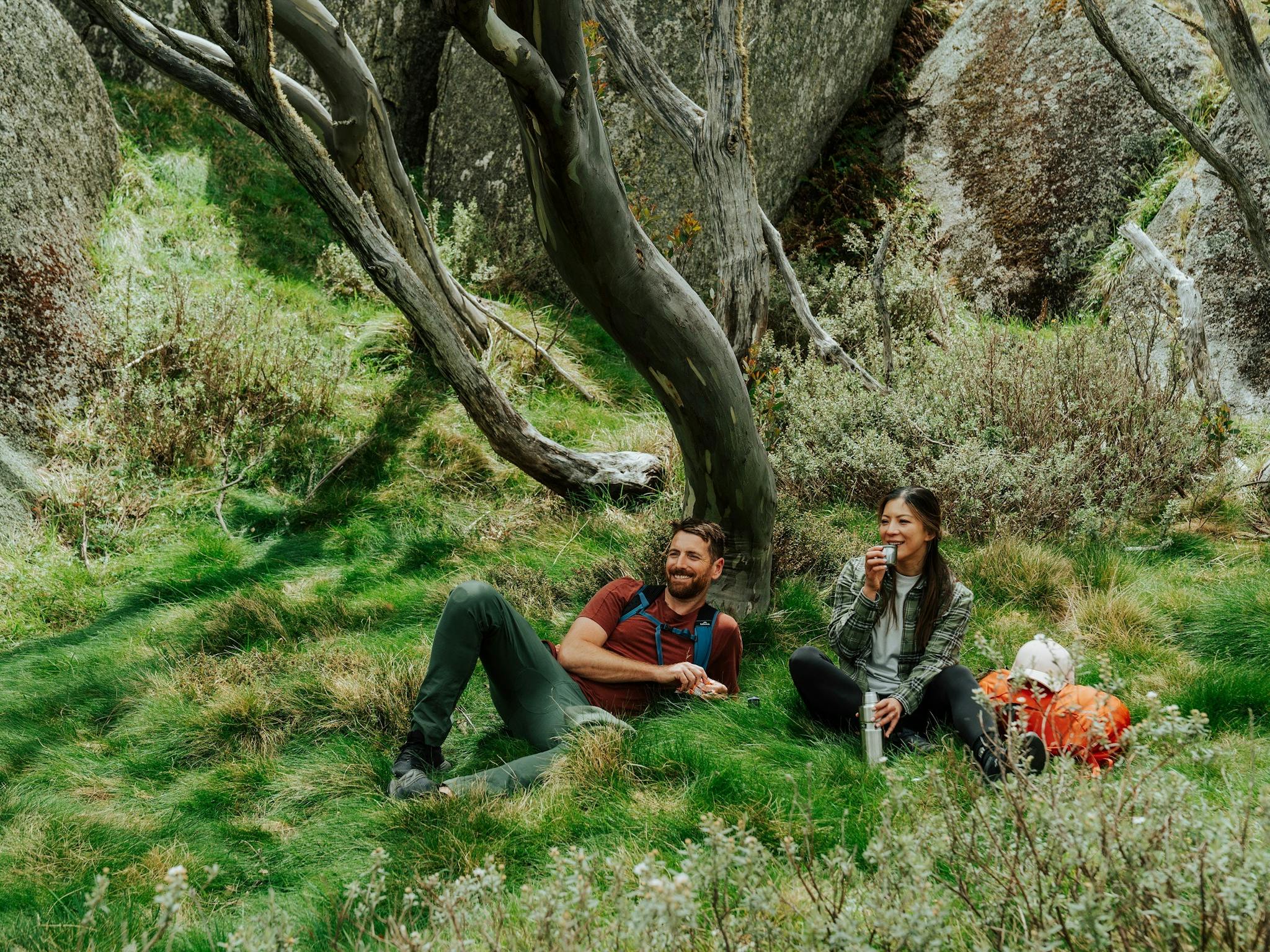 Two hikers resting on the grass in in Kosciuszko National Park.