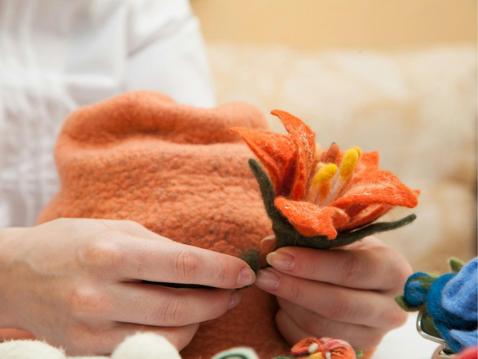 Felt hat making in process featuring an orange hat with decorative flower