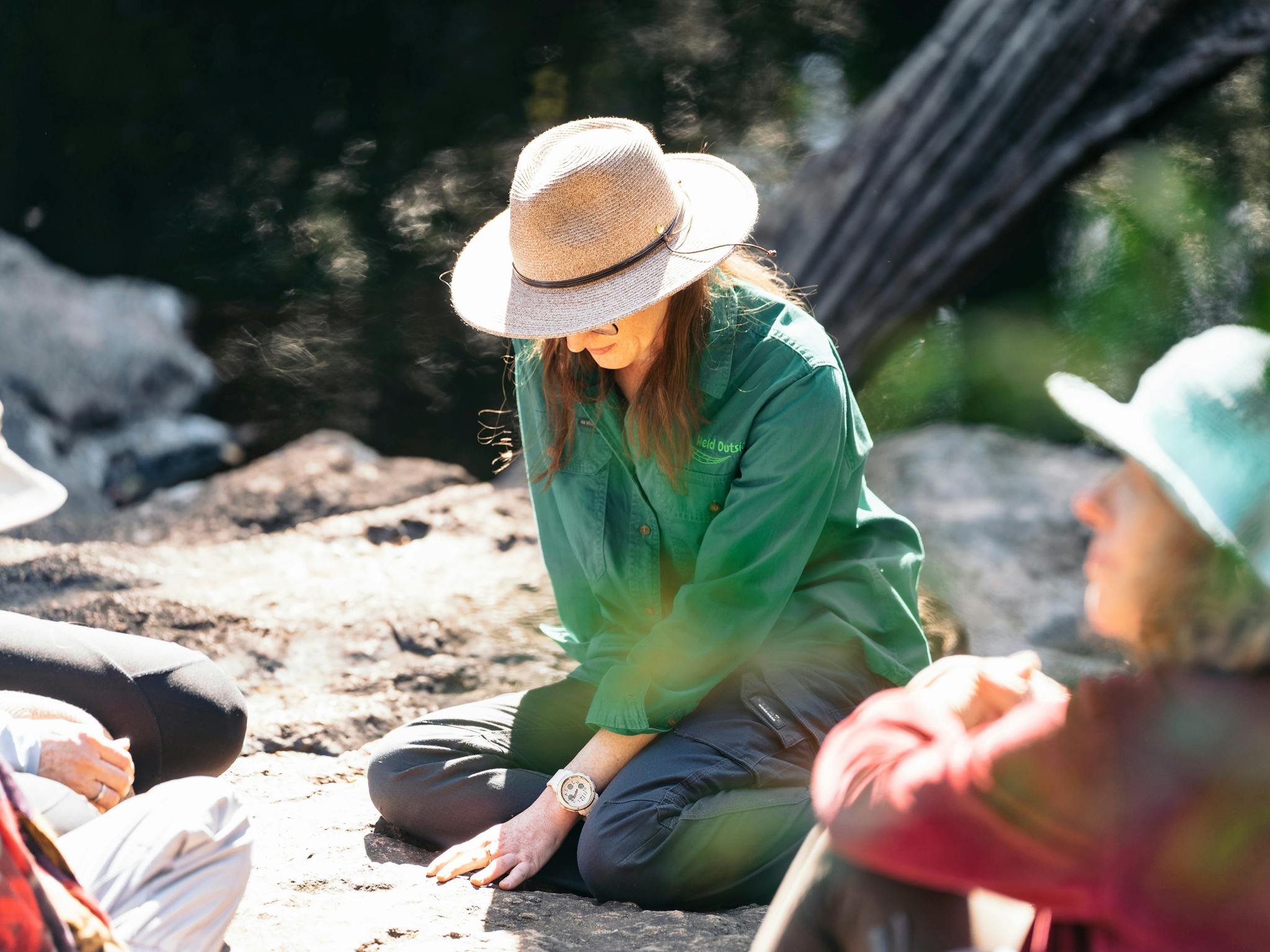 Women meditating with rocks and creek Women meditating with rocks and creek