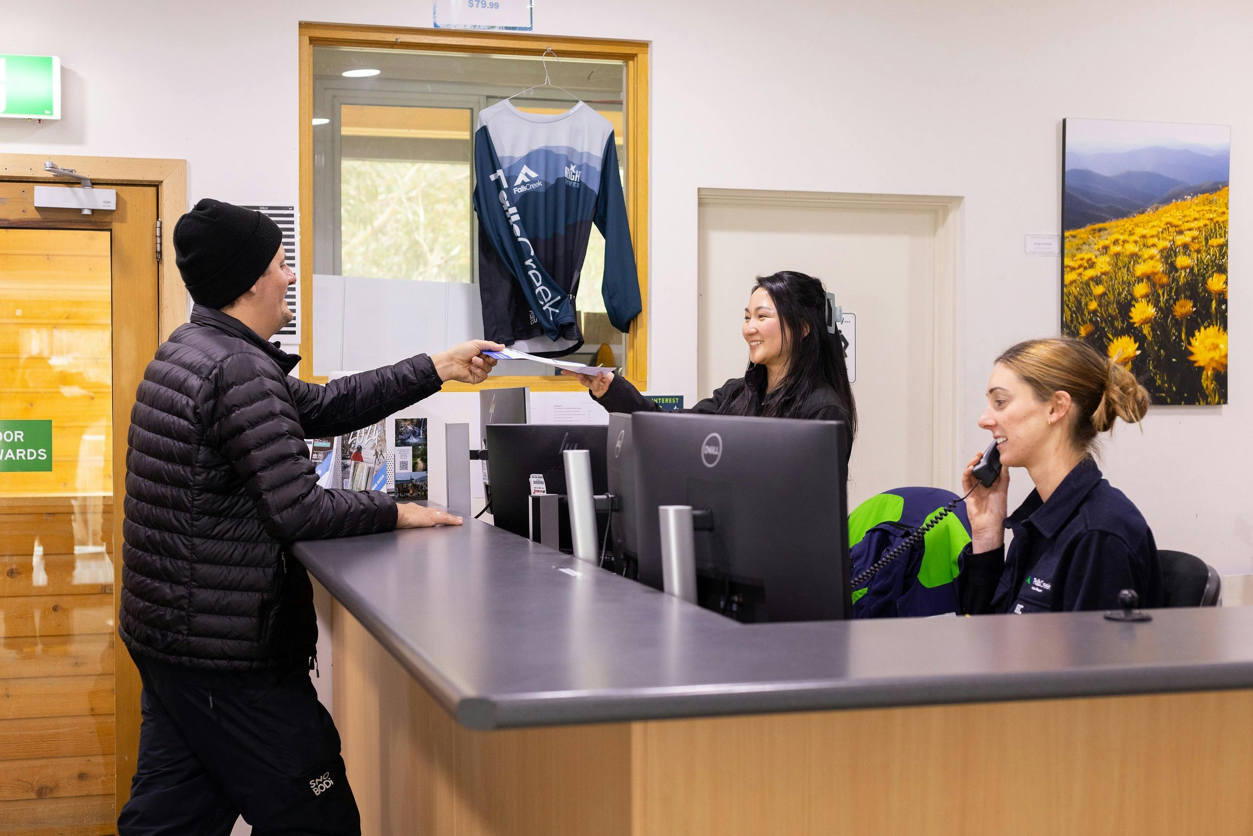 A male guest being handed a resort entry permit across the counter by a friendly staff member.
