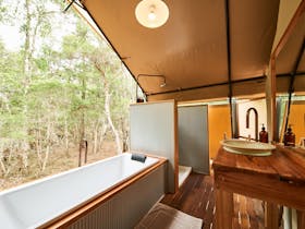 The Deluxe safari tent private outdoor bathroom looks out onto the bush.