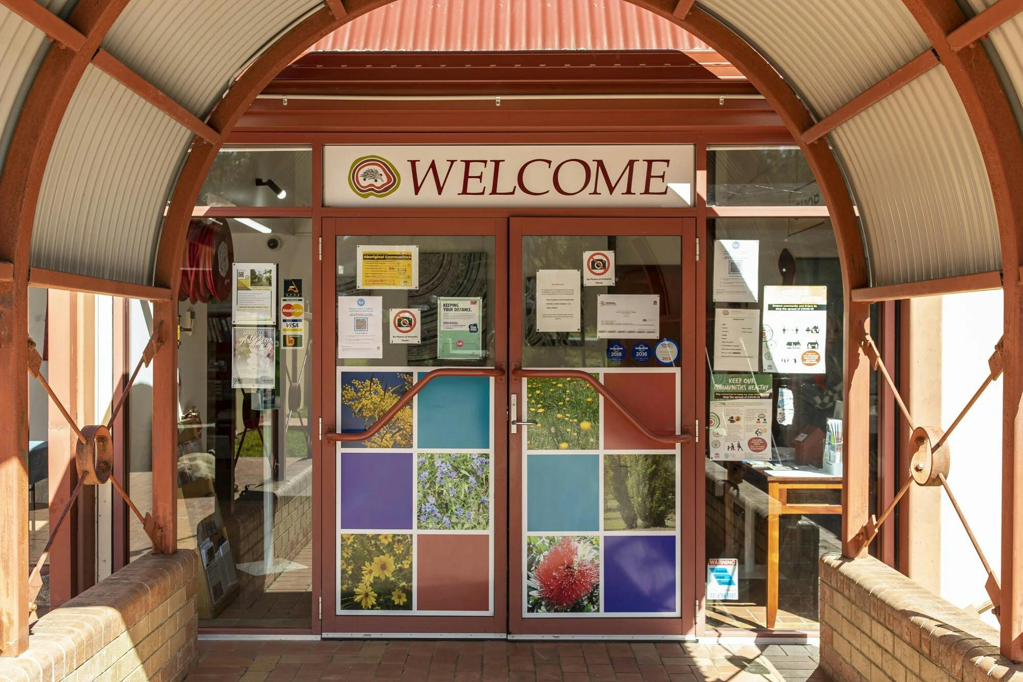 entry door to ACCKP, welcome sign sits above the door way and images of flora are on the door.