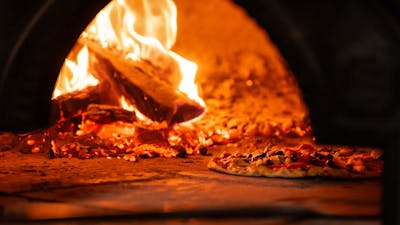 Pizza cooking in woodfired oven