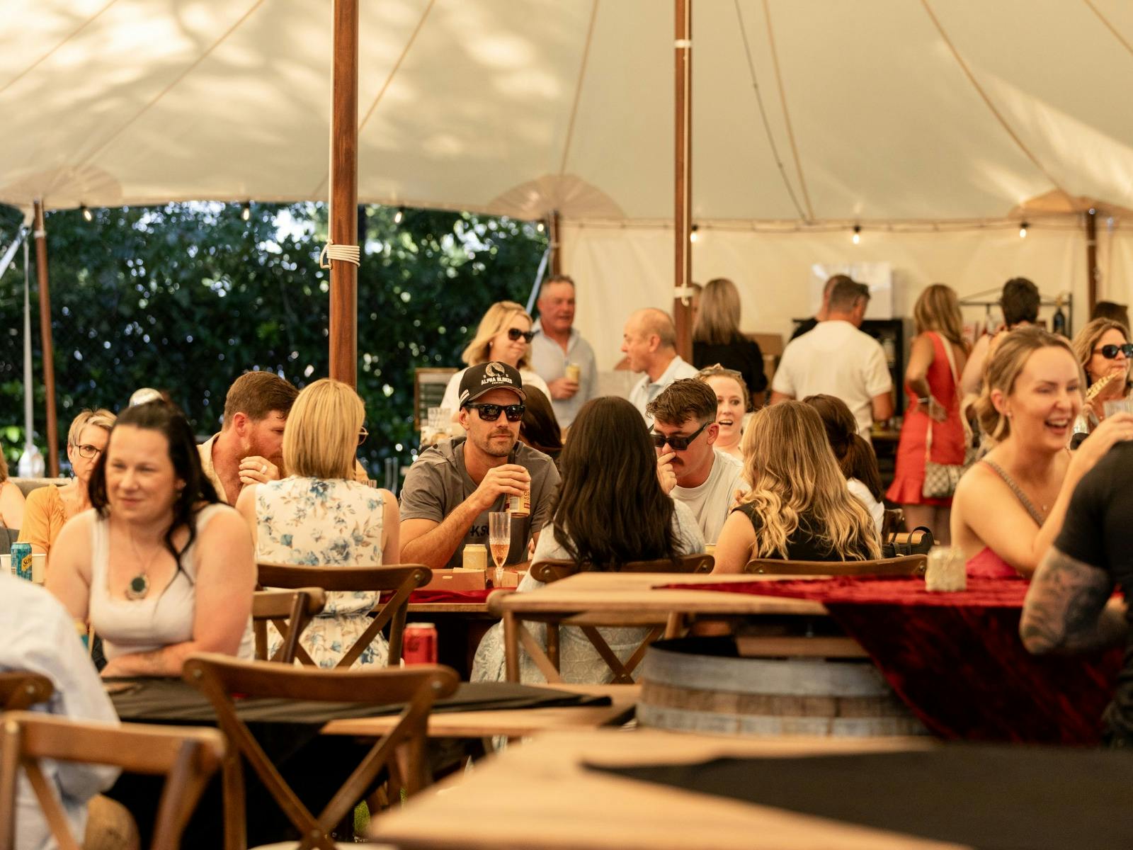 people sitting at wooden tables and chairs chatting and drinking