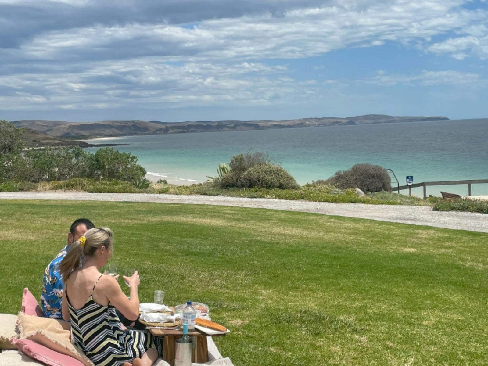 a couple looking our to sea with gourmet picnic