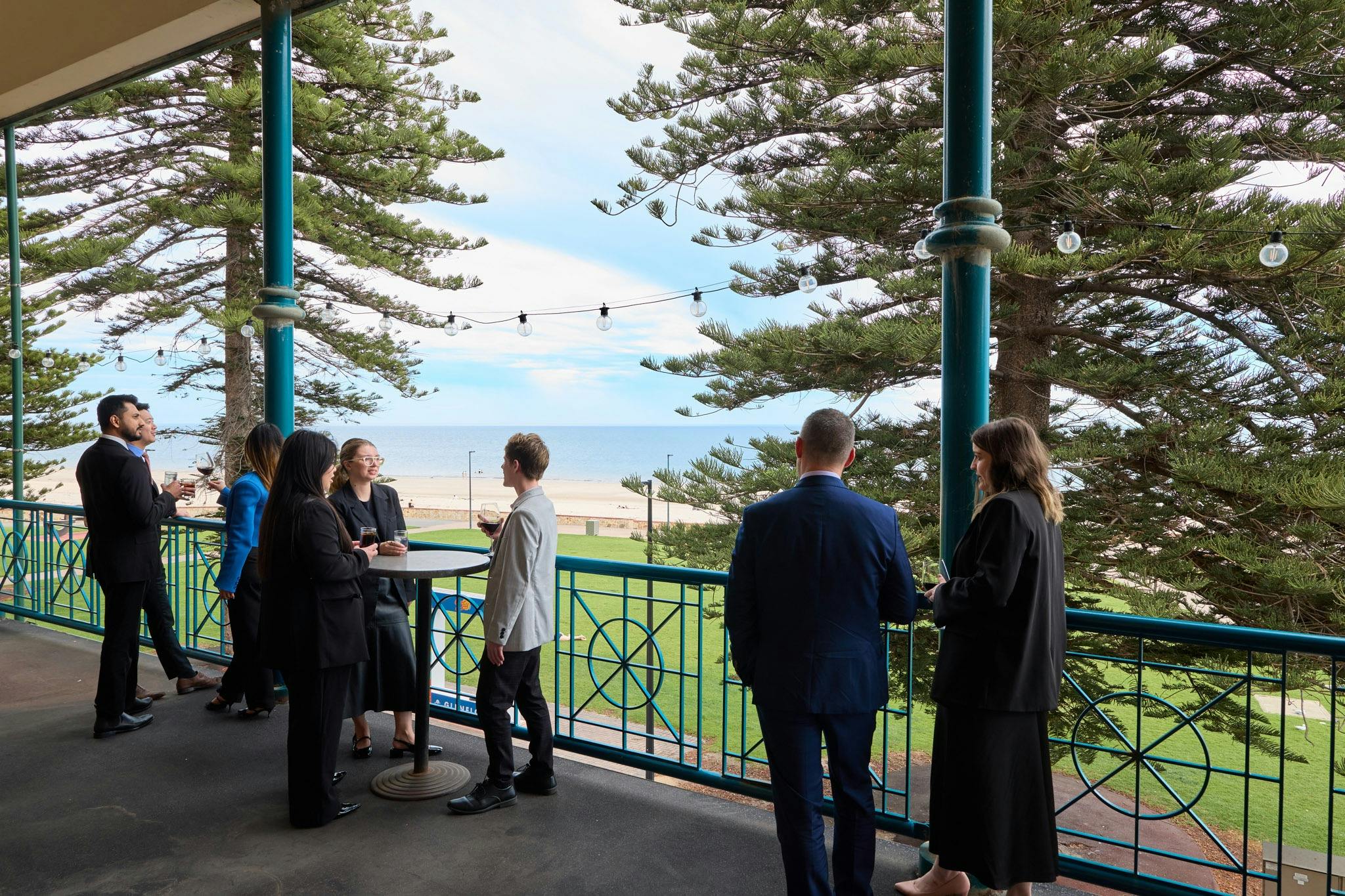 Colleagues on the Stamford Grand Adelaide Balcony, having a festive conversation in small groups.