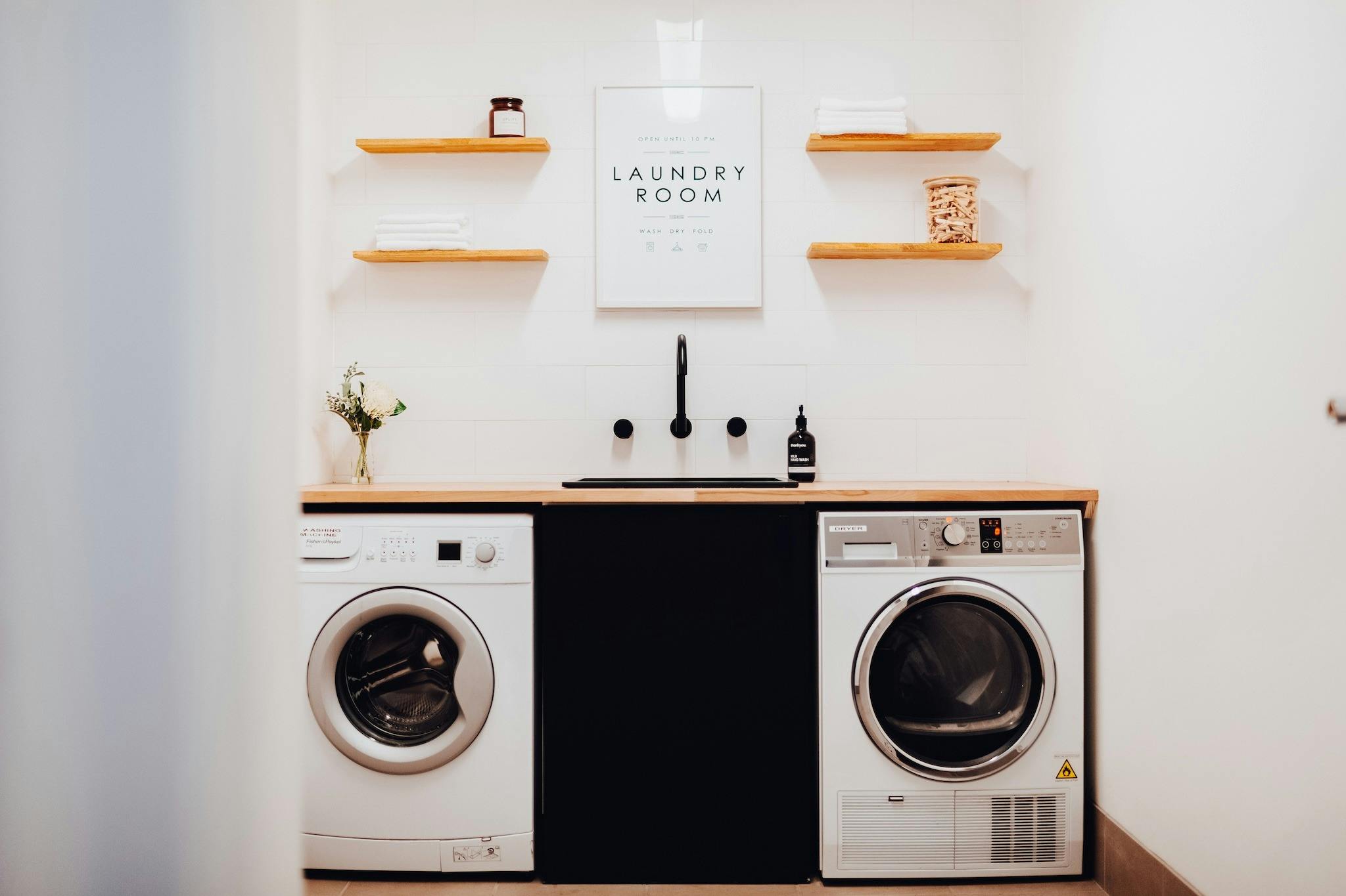 A glimpse into the common area laundry room, with a washer and dryer, sink, and bench space