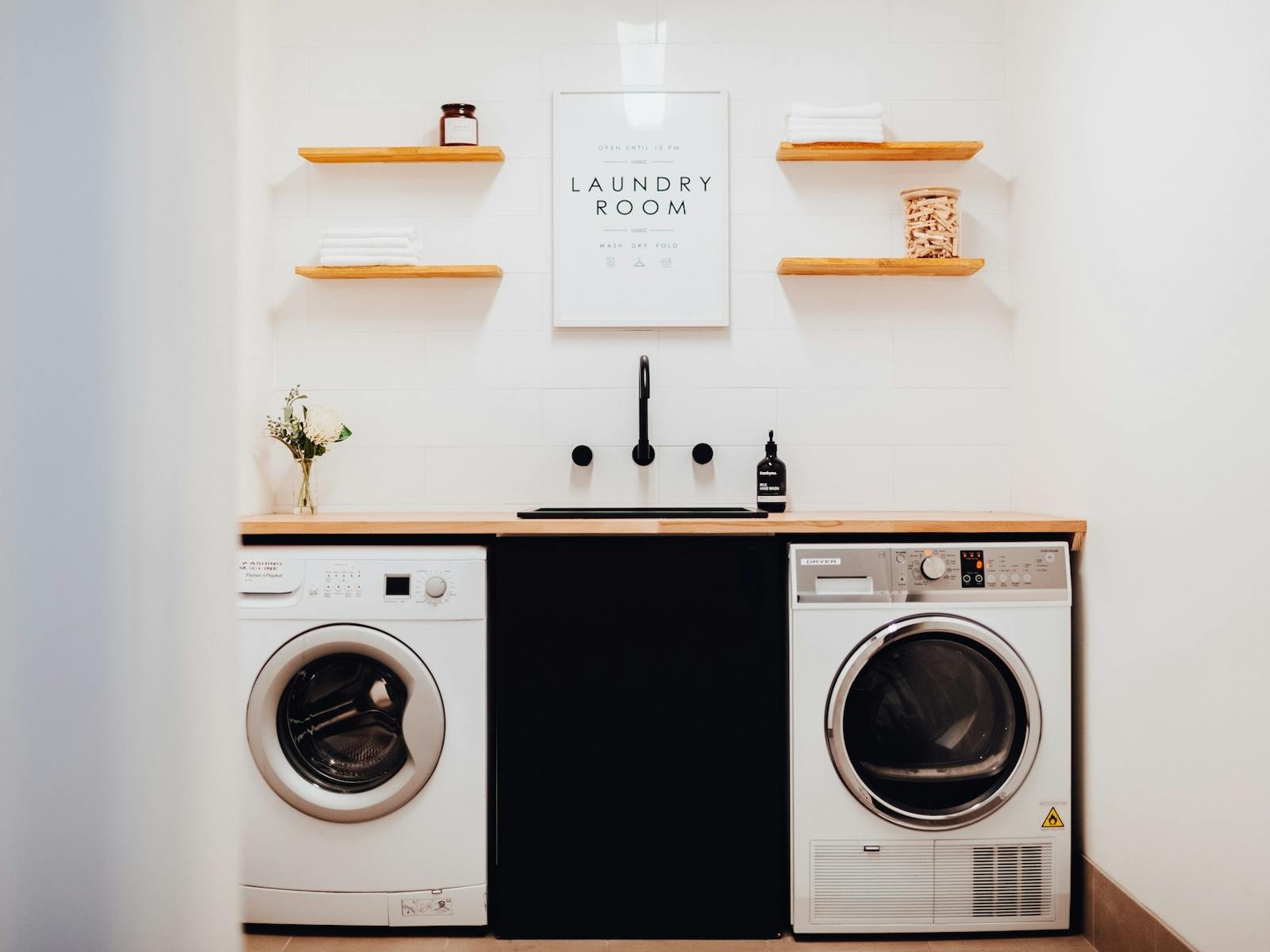 A glimpse into the common area laundry room, with a washer and dryer, sink, and bench space