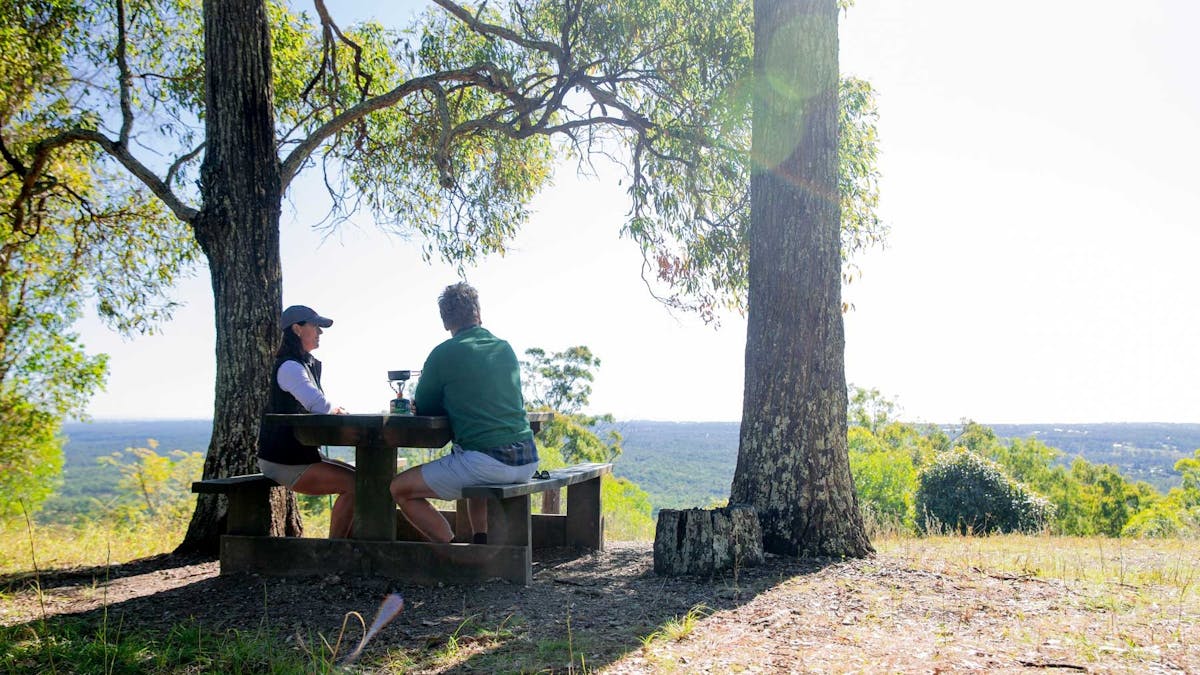 Man and woman seated at lookout bench enjoying the peaceful Redlands coastal view