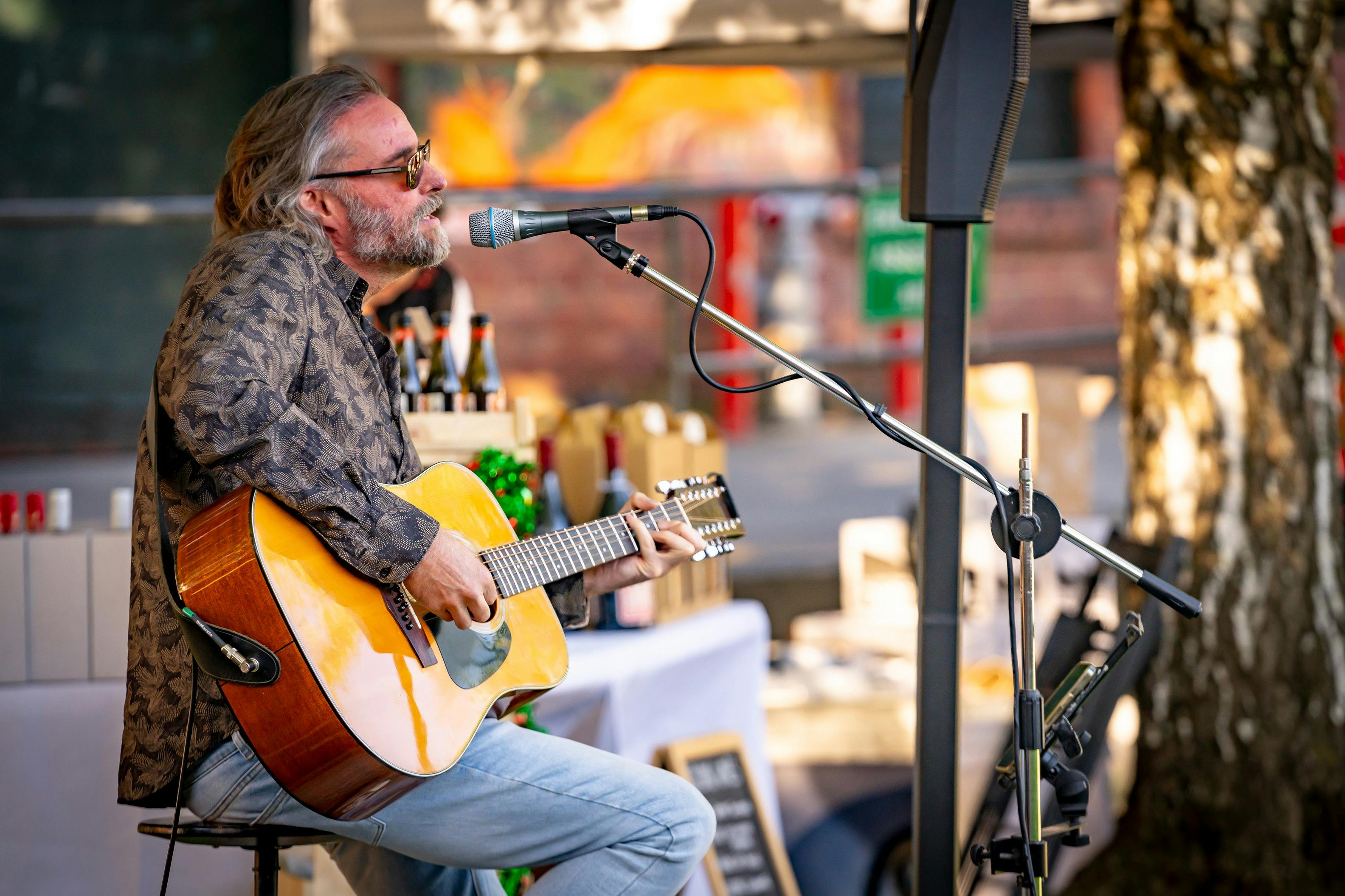 Musician performing live at FABRIK’s Handmade Christmas Market, seated and playing acoustic guitar