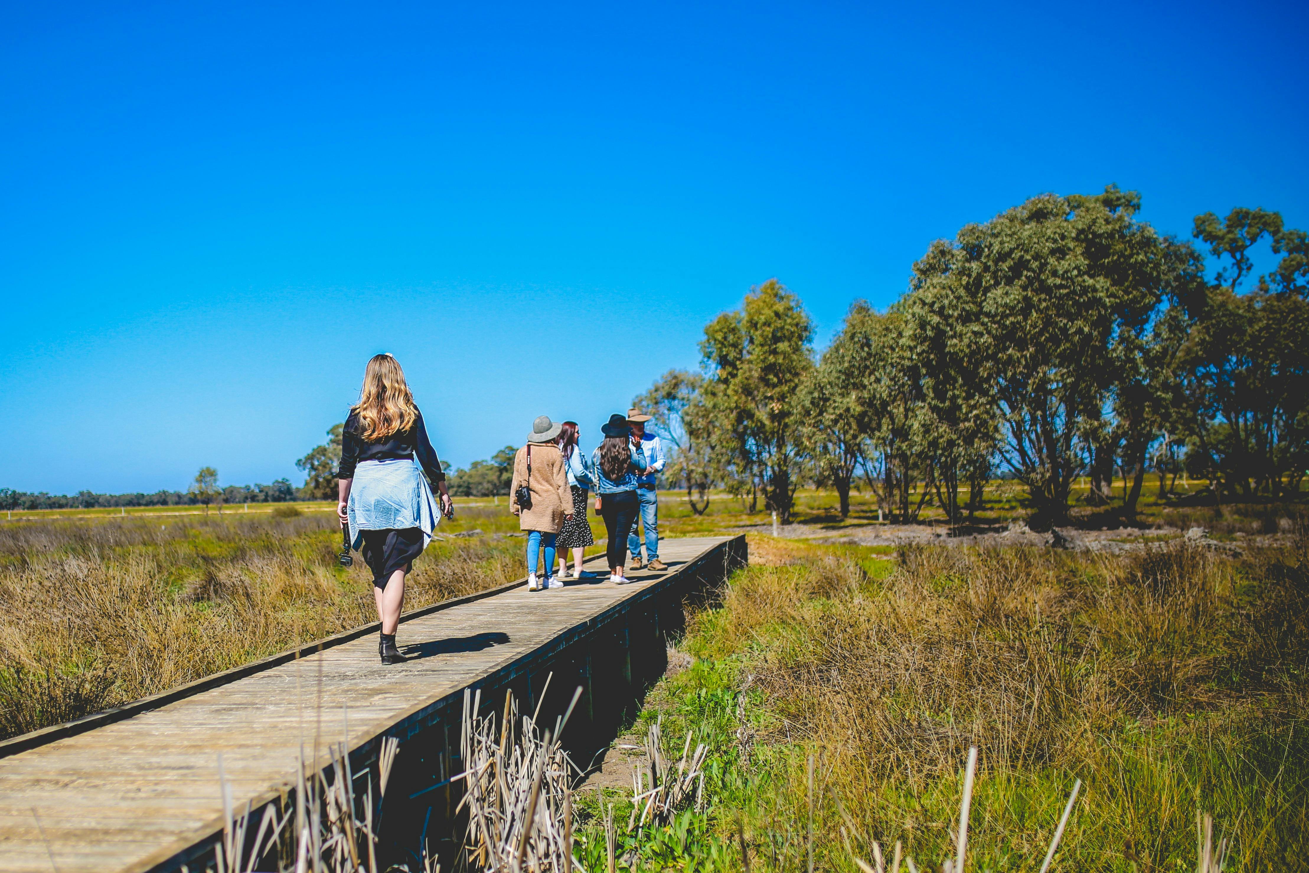 three people walking on a small bridge