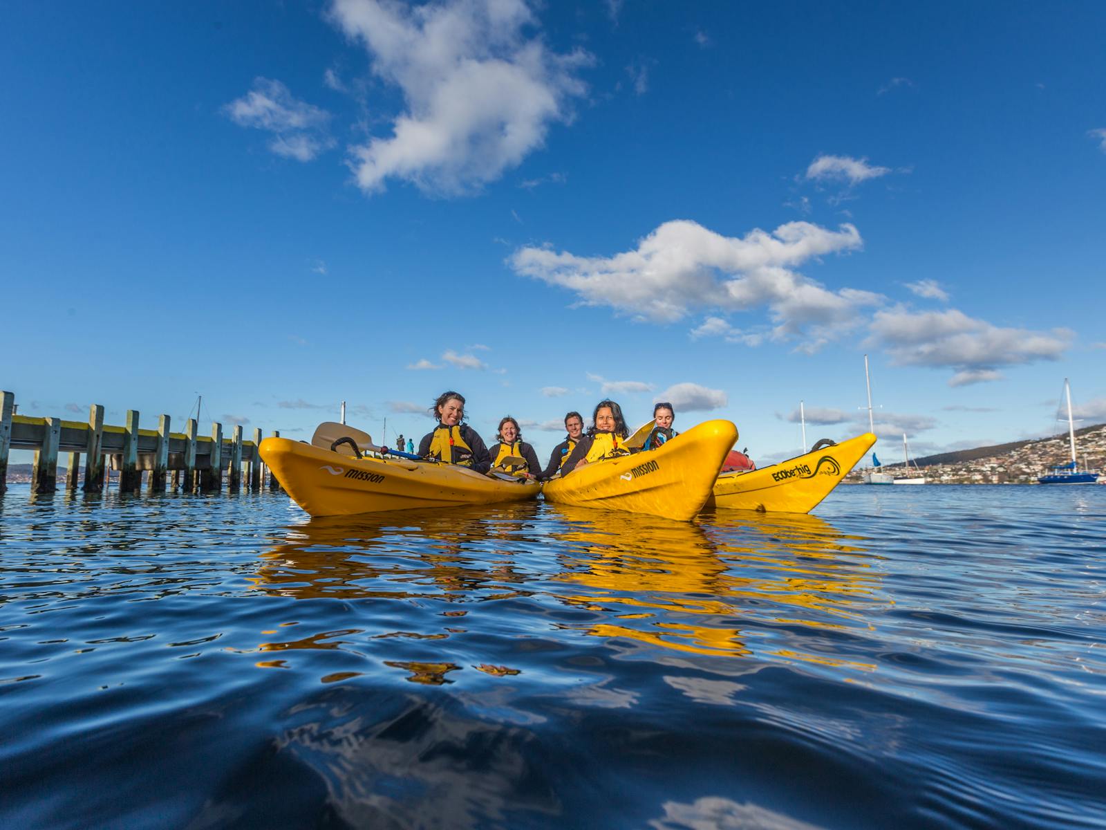 A group of kayakers relaxing in their kayaks on calm water on the Hobart waterfront