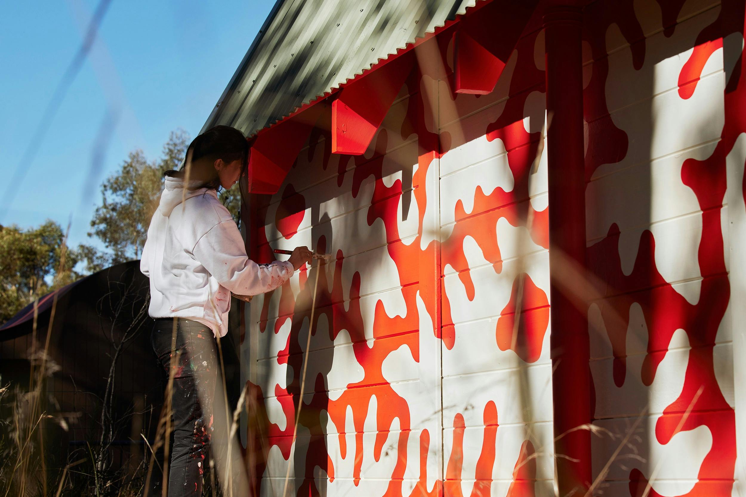 Artist Minna Leunig painting red and white patterns on a wall