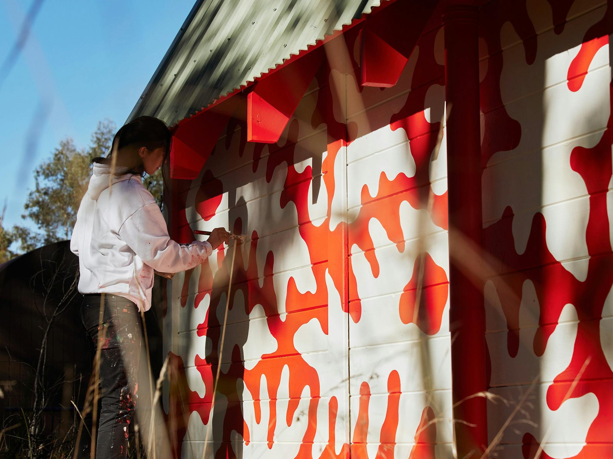 Artist Minna Leunig painting red and white patterns on a wall