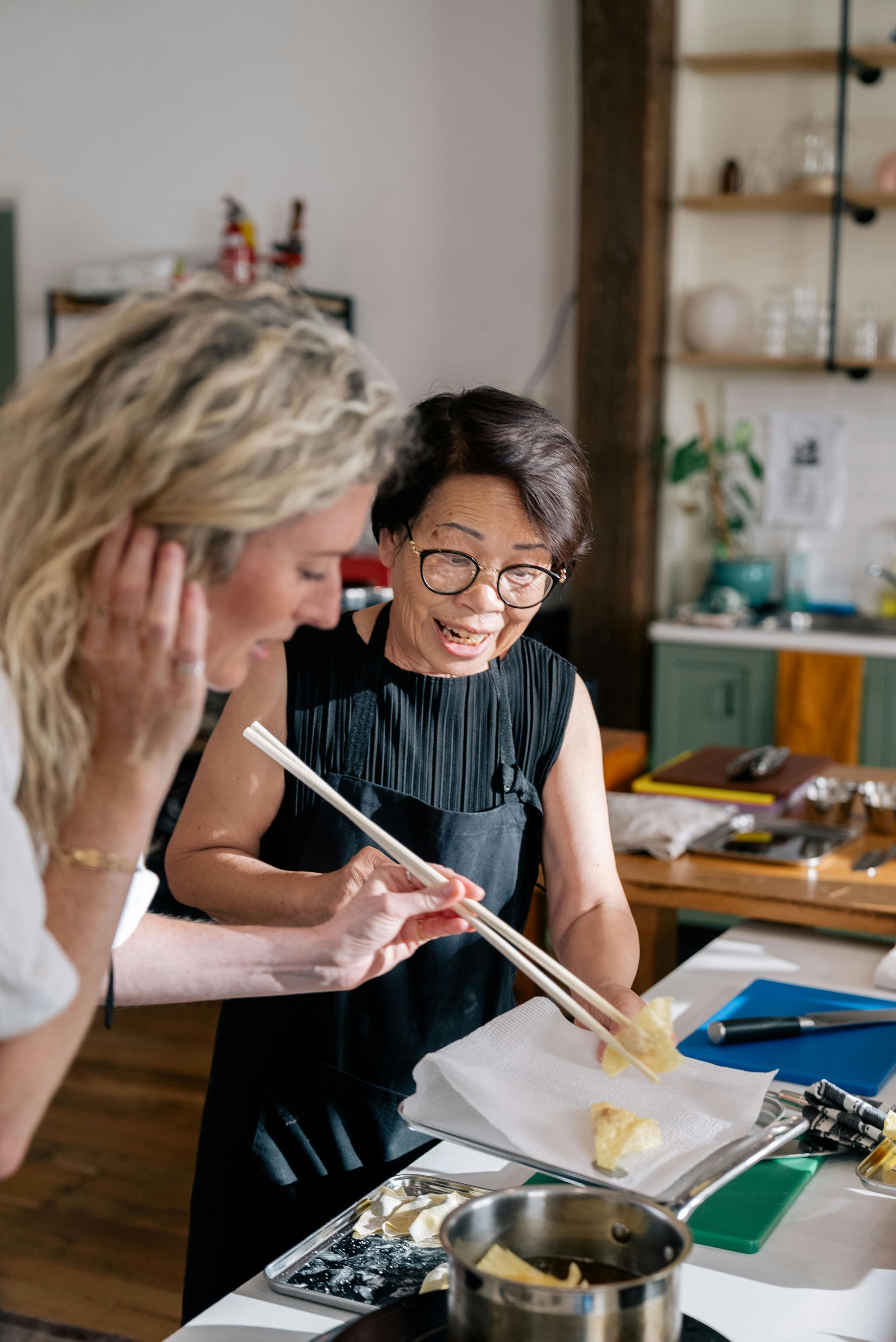 Mother teaching a class on frying dumplings to perfection