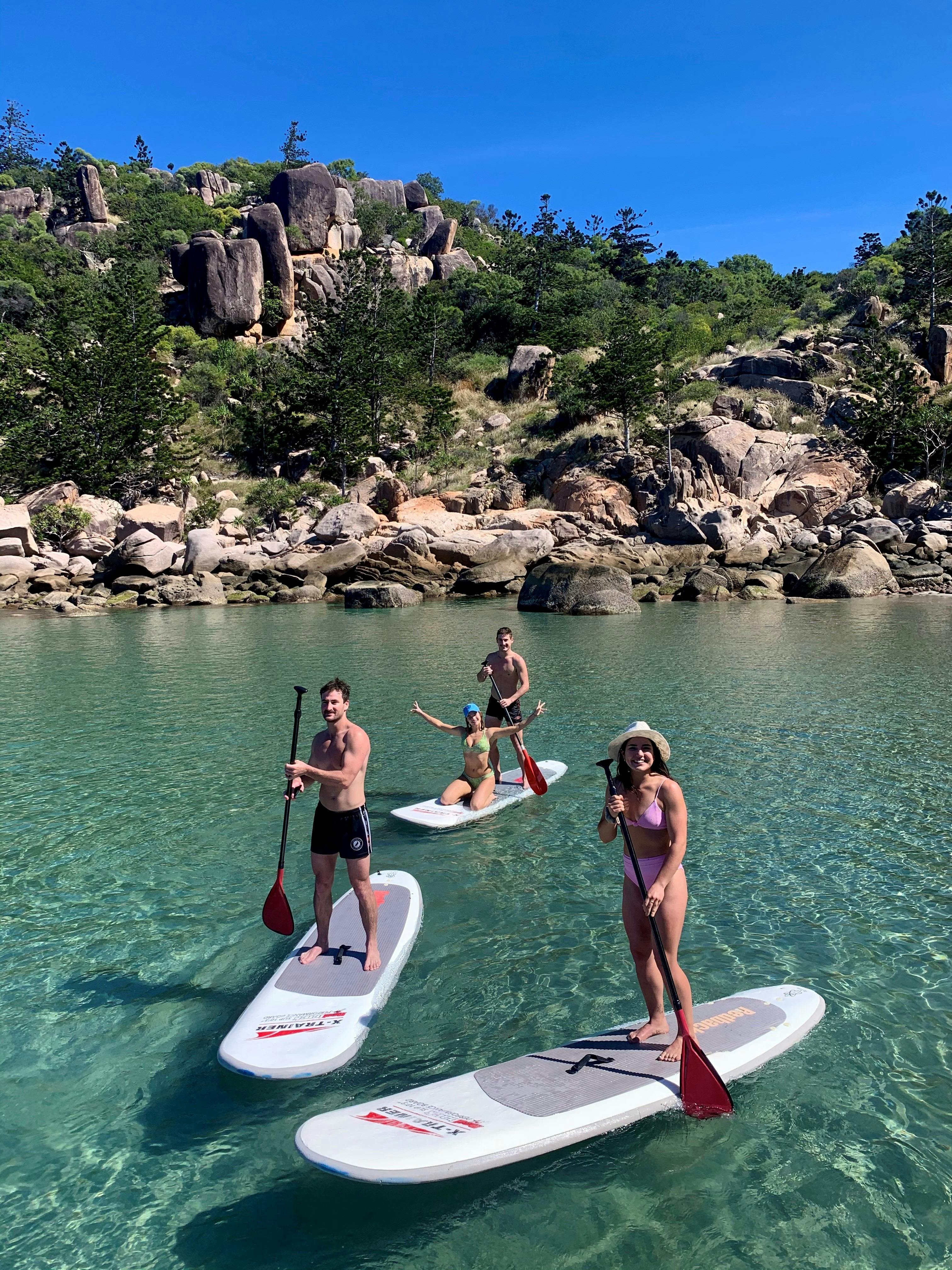 guest paddle boarding in a beach cove