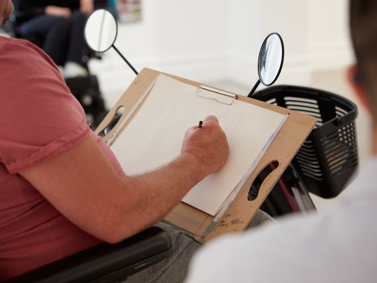 Motorised scooter user sketching an artwork on a clipboard