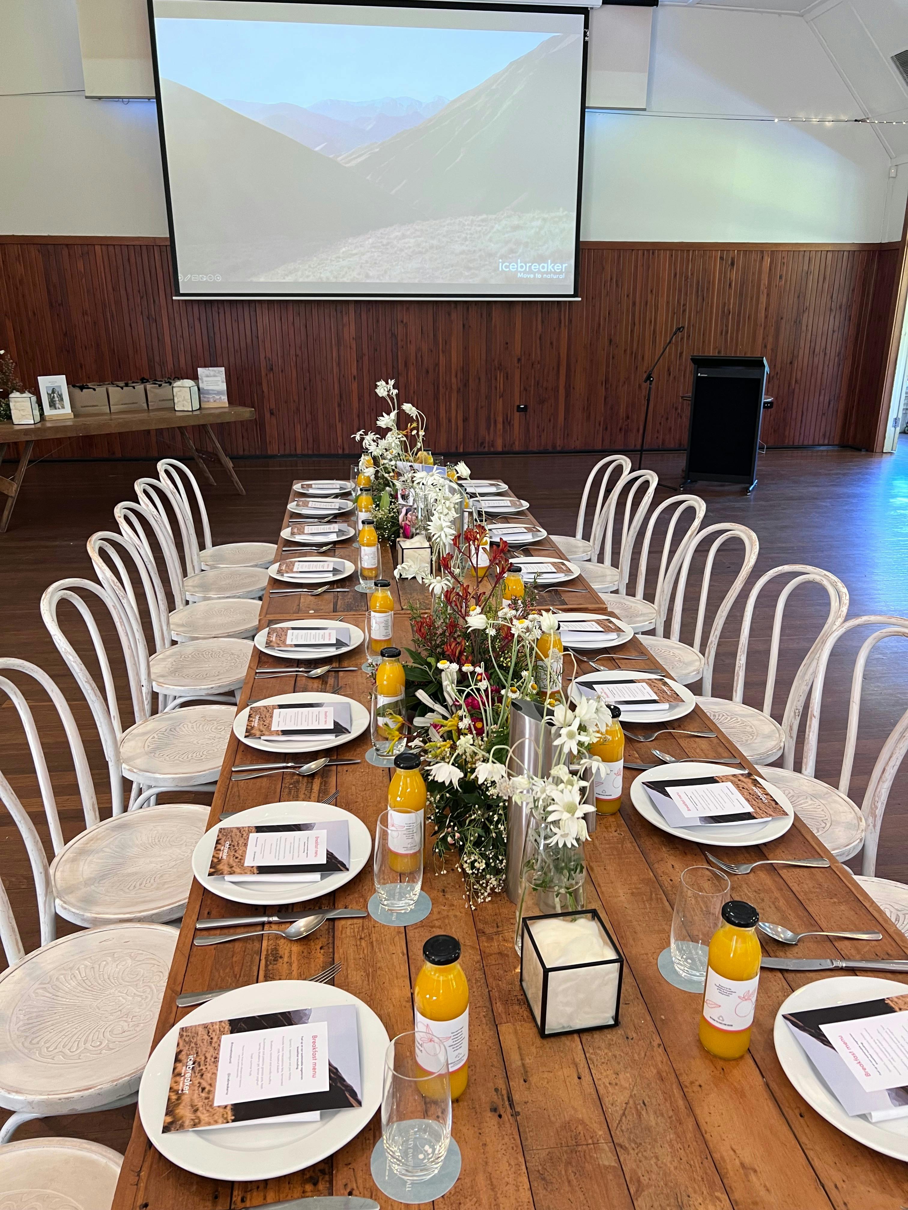 Timber table set with breakfast items and drop down screen in background