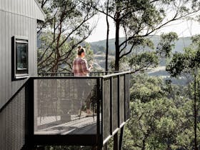 Hunter Huon Valley,  guest enjoying a glass of wine on the private deck overlooking the view