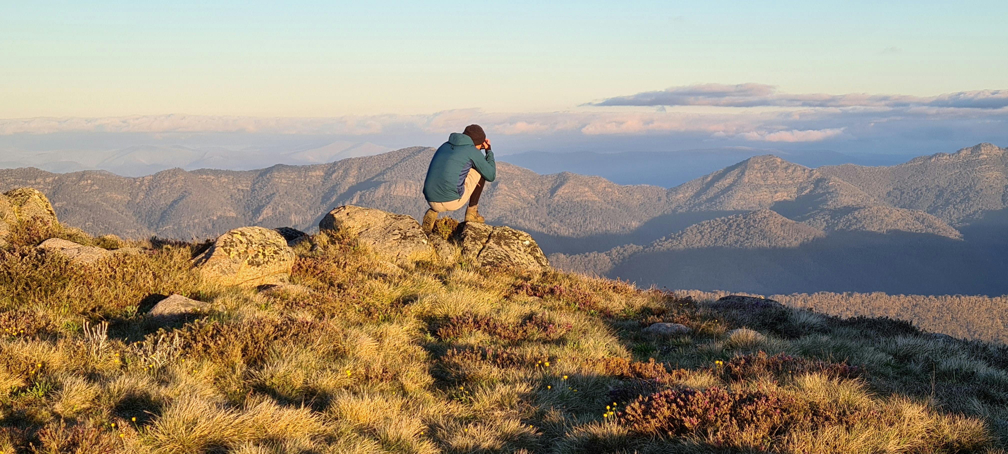 A hiker capturing breathtaking views from Mt Stirling on his camera.