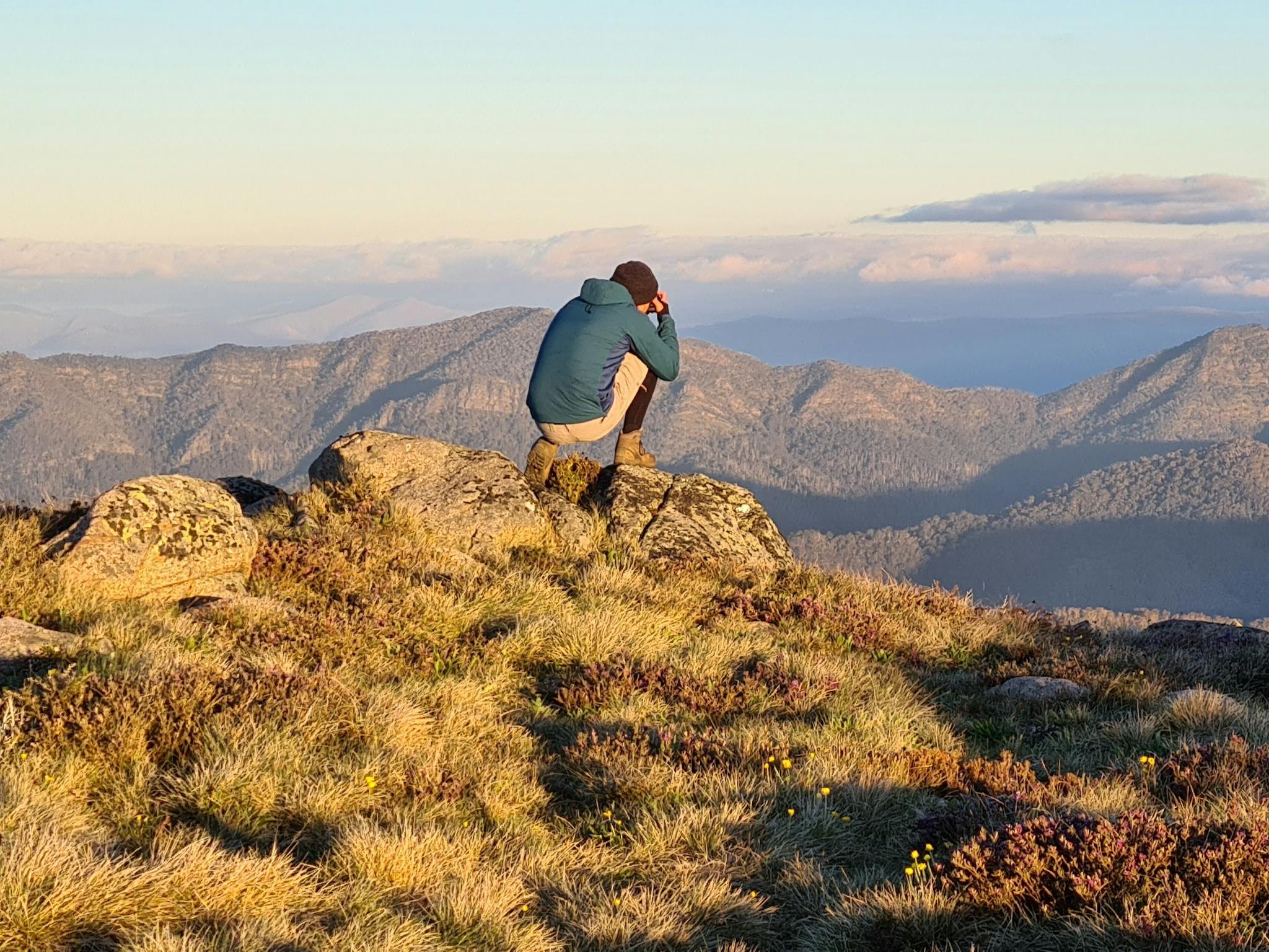 A hiker capturing breathtaking views from Mt Stirling on his camera.