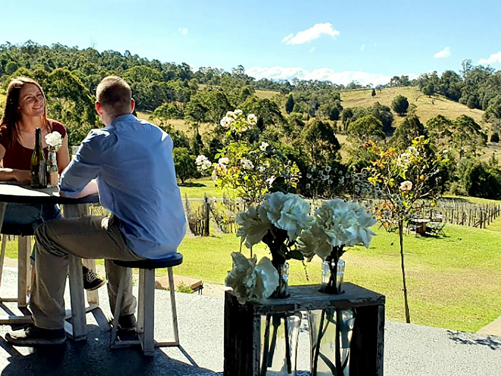 a couple having a wine with the winyard as a backdrop a couple having a wine with the winyard as a backdrop