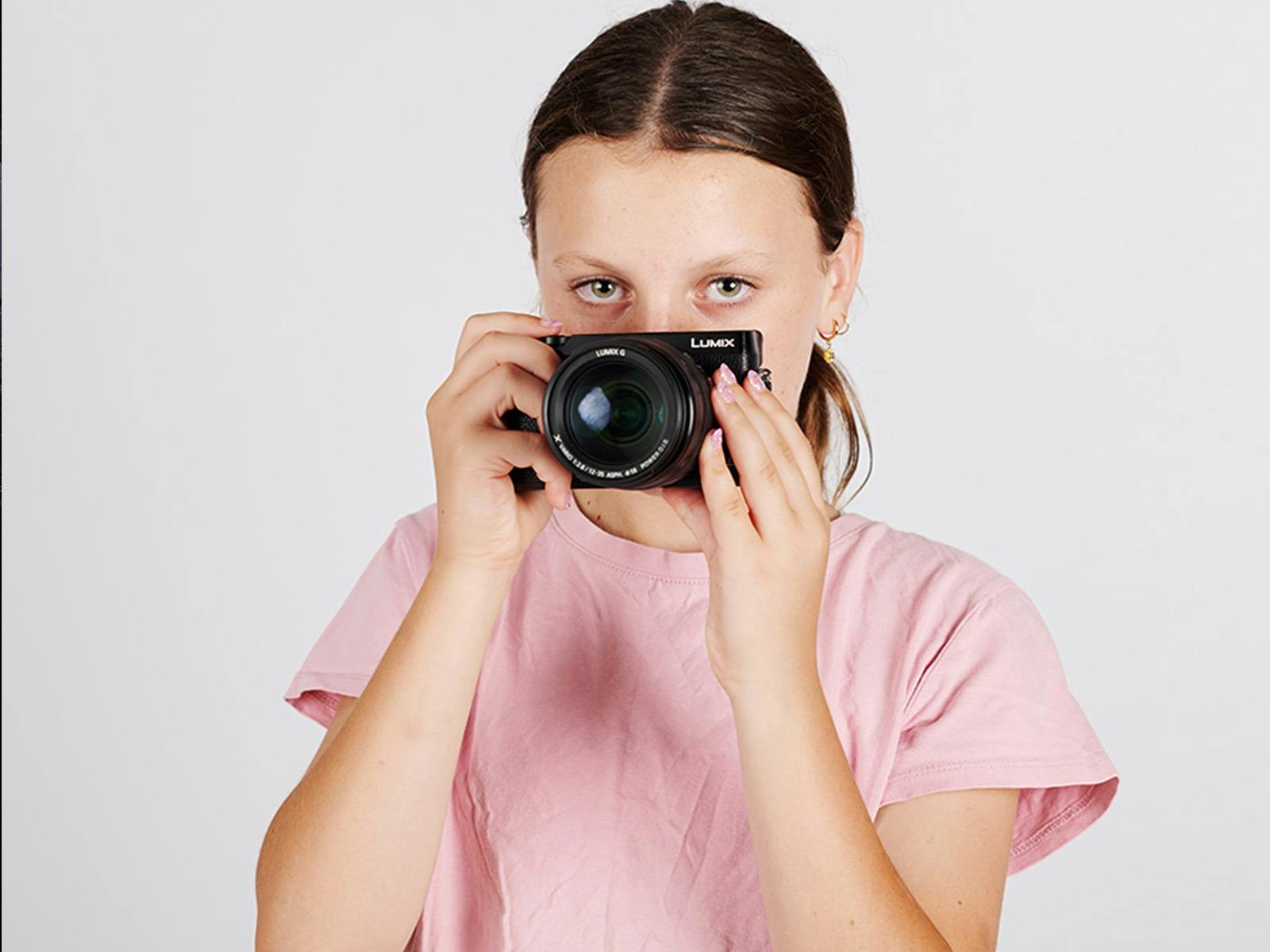 A young girl holds a camera to her face