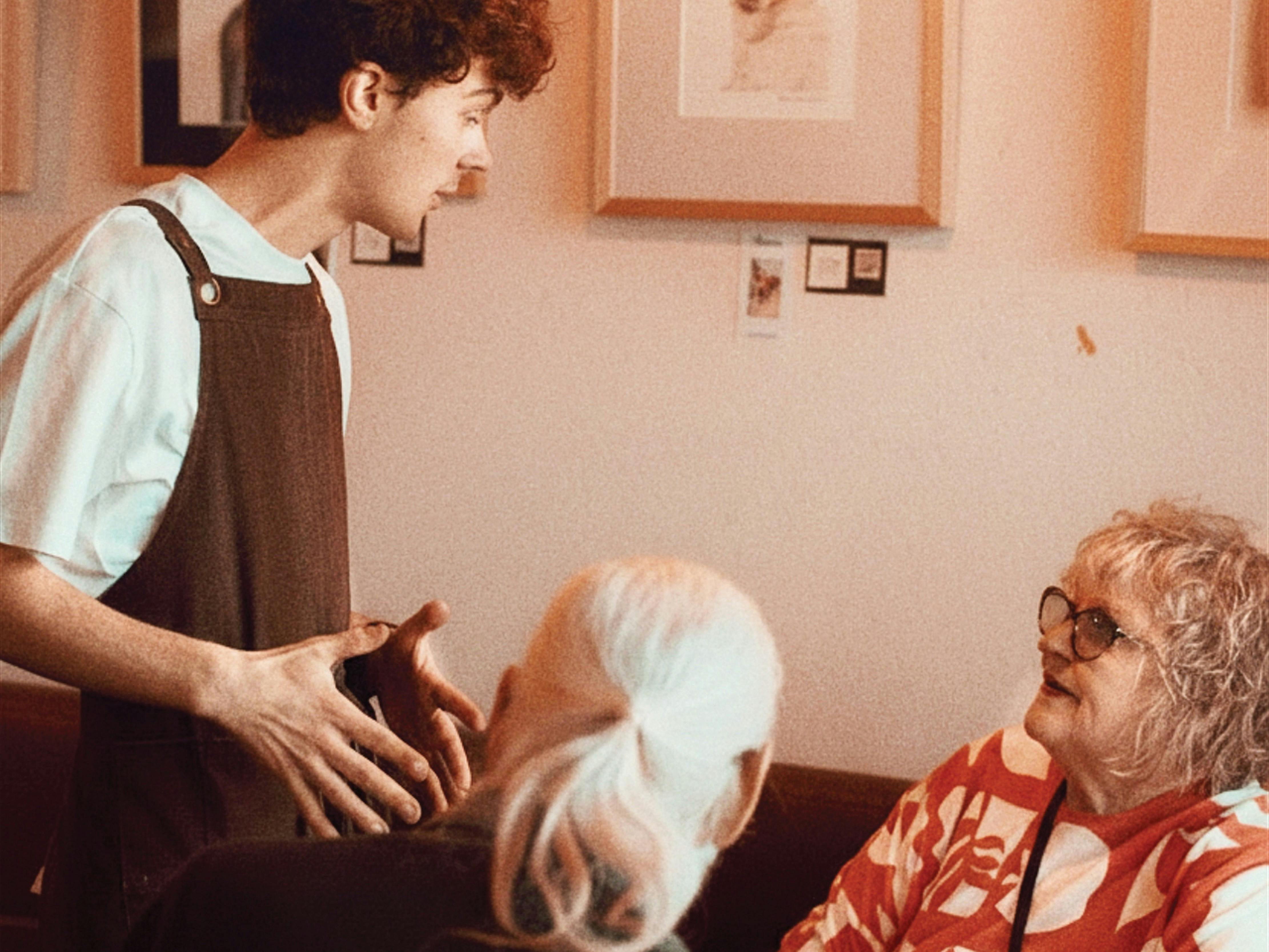 A team member at The General Food Store looking after customers sitting at a table.