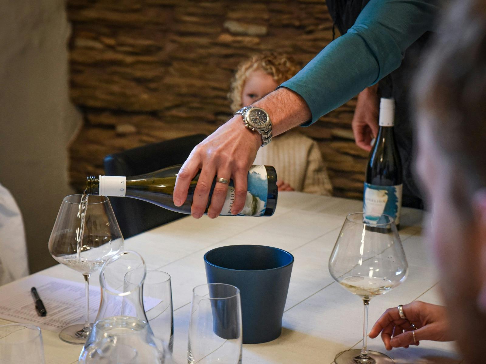 A man's arm pouring white wine