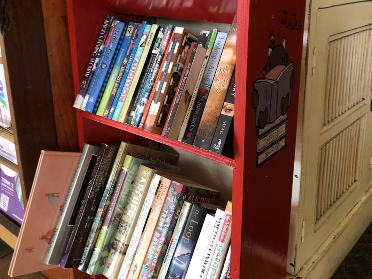 Red bookcase full of books for borrowing and sharing.