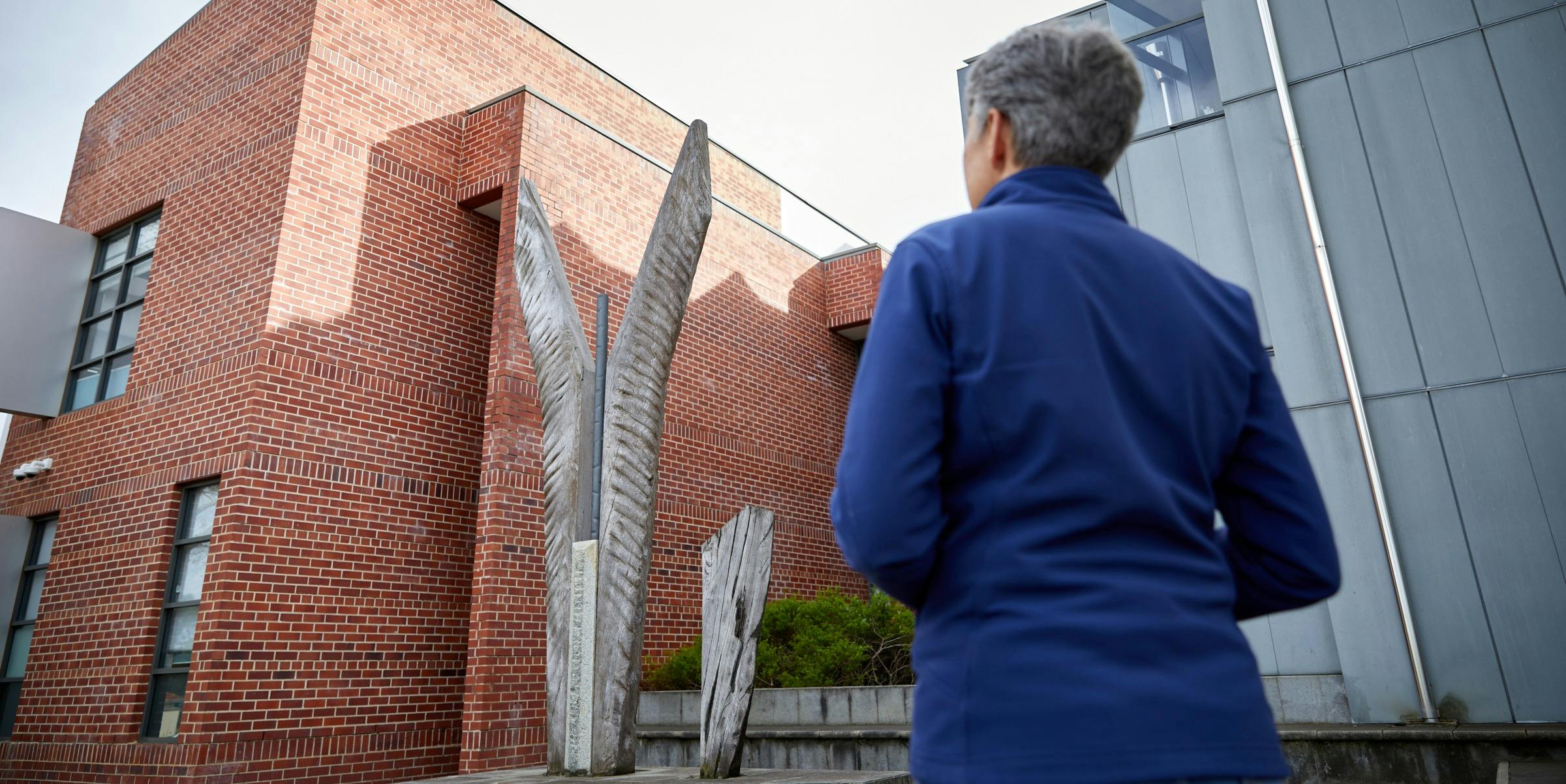 woman viewing large sculpture in front of brick building