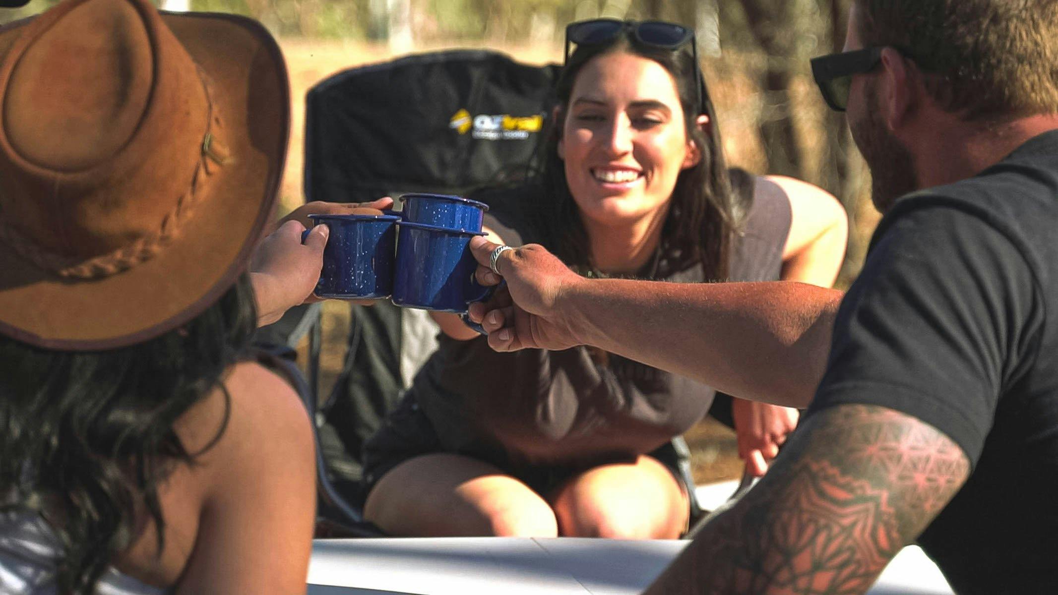 Three campers sitting around the campsite table cheering together