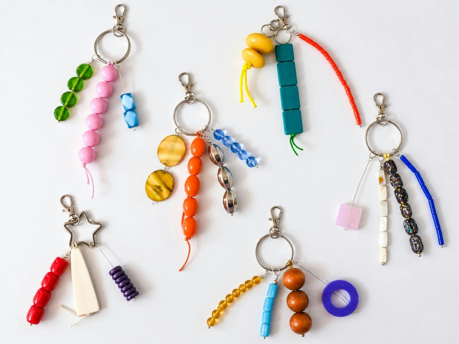 Colourful handmade beaded bag charms arranged on a white background.