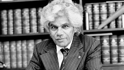 Neville Bonner sitting at a desk with books behind him