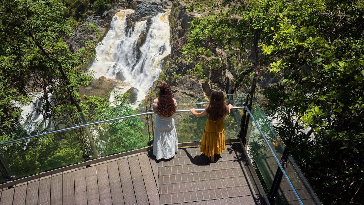 Two ladies facing away from the camera looking at the view in front of them of the barron falls