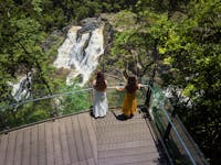 Two ladies facing away from the camera looking at the view in front of them of the barron falls
