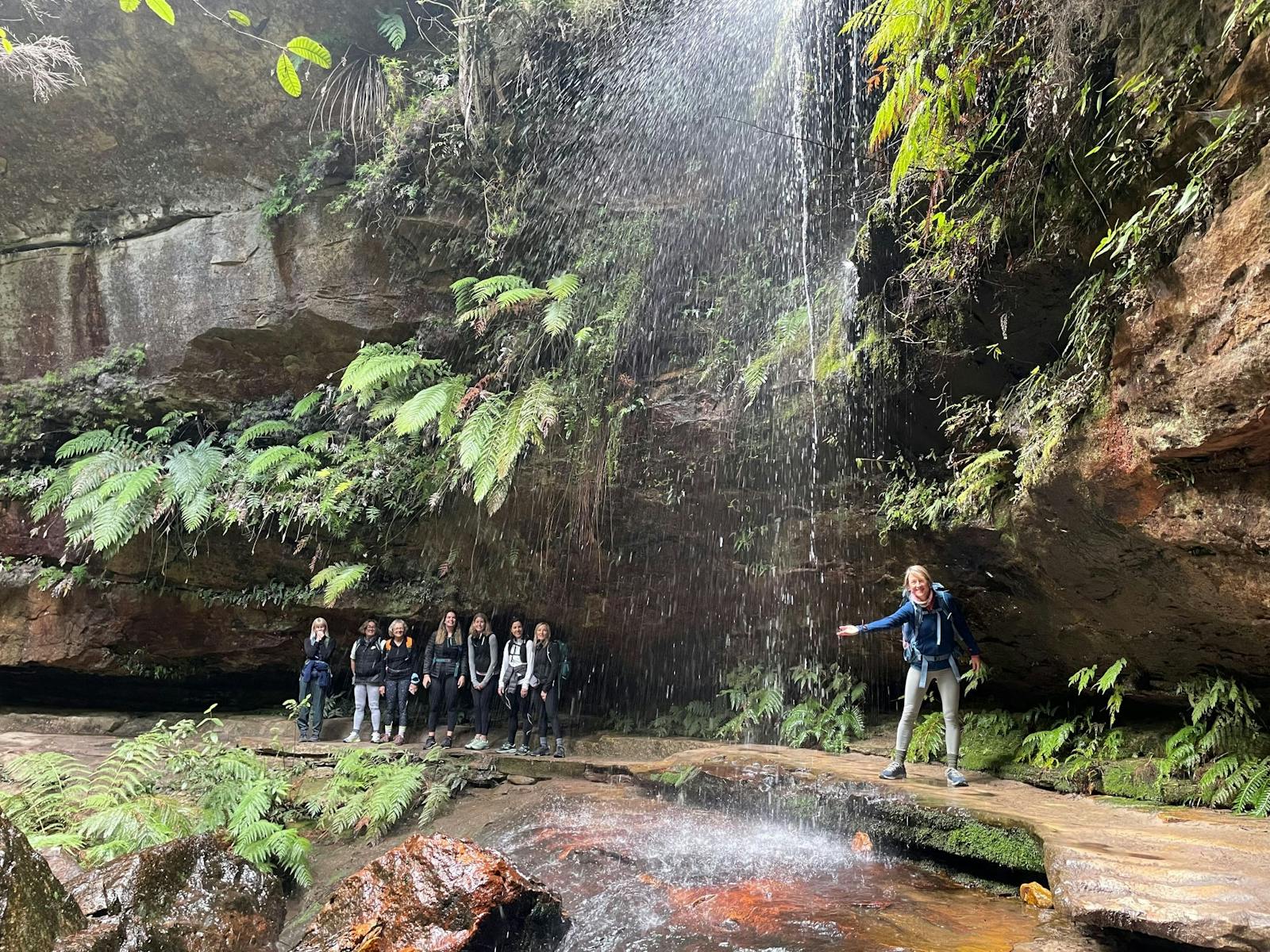 Group exploring behind waterfall