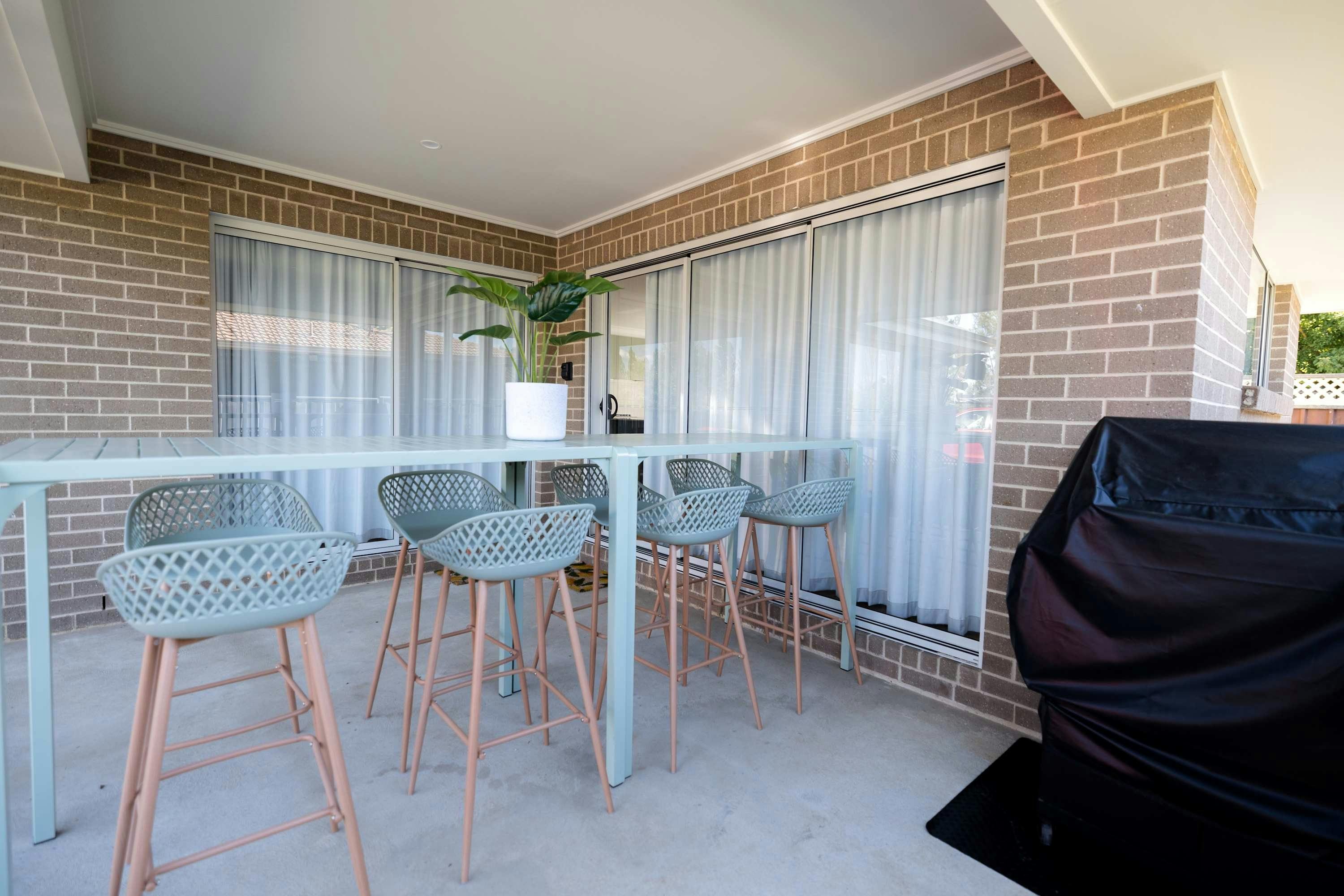 8 high green stools and a high bar table for guests to enjoy the outdoor area, also with a bbq.