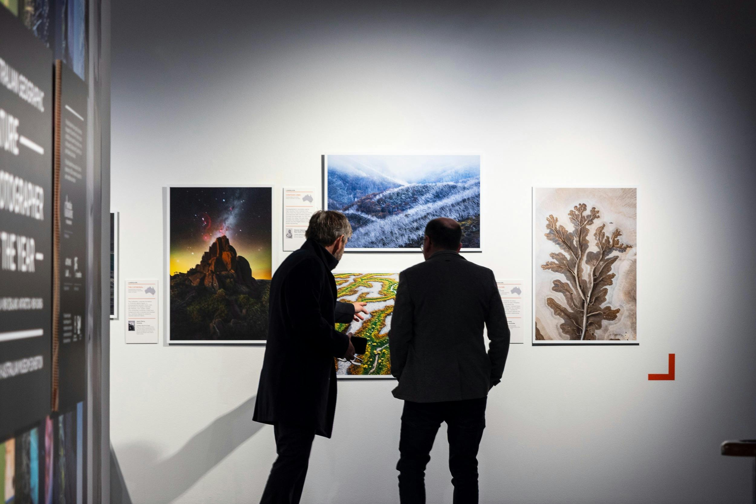 Visitors discussing framed landscape and botanical photographs on display